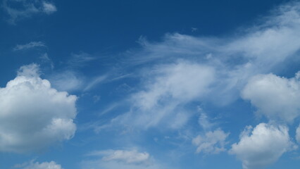 Blue clear sky with white cumulus and cirrus on different layers spindrift clouds background. Light white cirrus clouds in blue sky on a summer day. Timelapse.