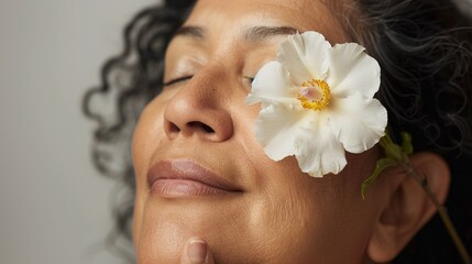 Naklejka premium A serene woman with her eyes closed gently touching her chin and a delicate white flower placed On her cheek.