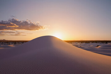 serene sandy desert landscape at sunset, showcasing soft ripples in dunes and warm glow from setting sun. tranquil scene evokes sense of peace and natural beauty