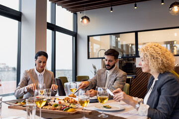 Smiling coworkers in restaurant talking during business lunch.