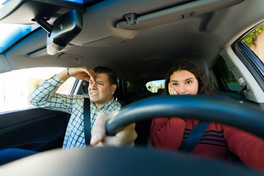 Anxious dad instructing his teen daughter in driving and grabbing the steering wheel to avoid danger