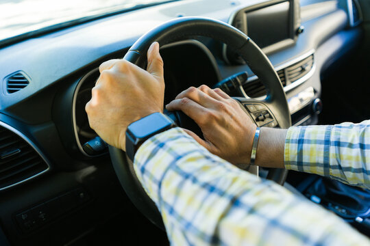 Man with smartwatch driving modern car, close-up of hands on steering wheel honking on the claxon to avoid an accident