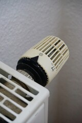 Close-up of a white radiator thermostat. A hand adjusts the knob to set the temperature. Perfect for heating, energy efficiency, and home comfort themes.