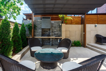 Backyard outdoor bbq zone with pergola, fireplace and hanging chair. Summer party place