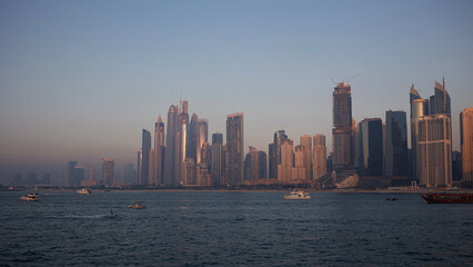 Obraz premium Dubai Marina, view of the shore skyscrapers, evening time, boats are on the water and
