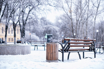 park bench on a winter alley at snowfall. bench with snow after snowstorm or in snow calamity in europe