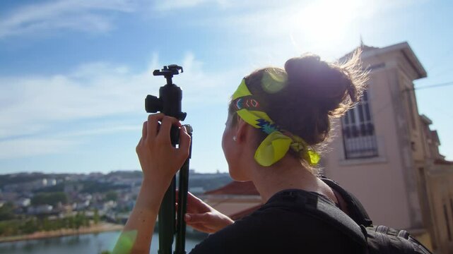 Girl wearing a yellow headband, holding a tripod and taking in the panoramic view in Coimbra, Portugal