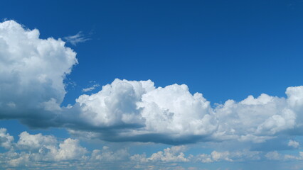 Clouds running across the blue sky. White puffy and fluffy clouds on blue sky. Time lapse.