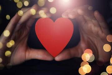 Woman holding hands with red heart on wooden background, top view
