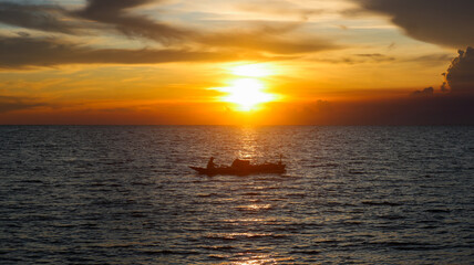Fototapeta premium Traditional Indonesian fishing boat. Horizon line between sky and sea. Dramatic sunset and clouds.