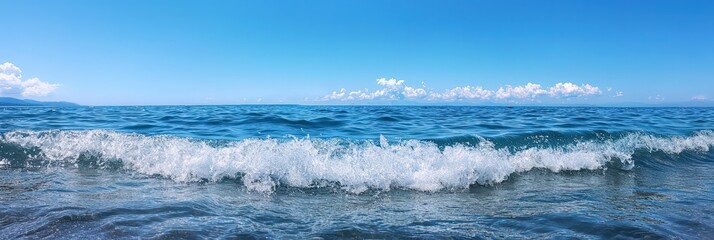Obraz premium Large wave crashes on calm ocean water under a clear blue sky