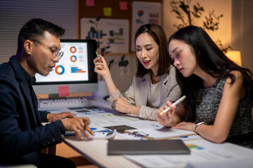 Three women are sitting at a table with a computer monitor in front of them