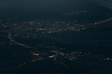 Aerial view from airplane window of buildings and bright illuminated streets in city residential...