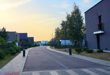 Modern luxury Villa. Street Road in Contemporary Residence. Modern Prefab house. Home with lawn, shrubs, green courtyard in sustainable enviroment. Family House in Gated Community. Landscaping at home