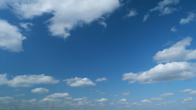 Floating fluffy cumulus clouds. Beautiful sunny blue sky with wispy smoky white stratocumulus clouds. Timelapse.
