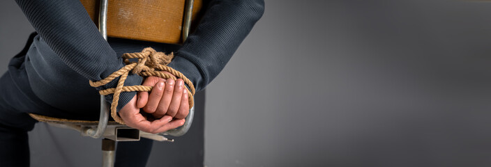 kidnapped man's hands tied with rope, criminal concept