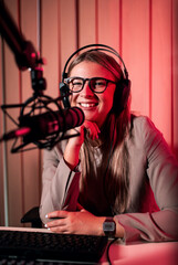 Portrait of young female podcaster making podcast from her home studio looking at camera.