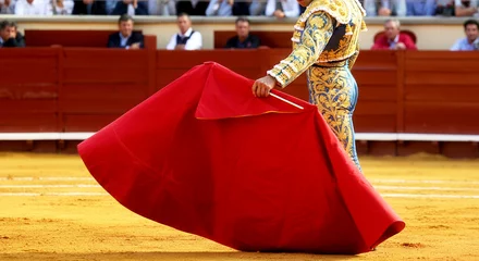 Fototapete Spanish bullfighting tradition with matador holding red cape in arena © Olga Davydova