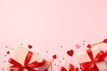 Valentine's Day pink gift boxes wrapped in red ribbons, surrounded by small red and pink hearts and...