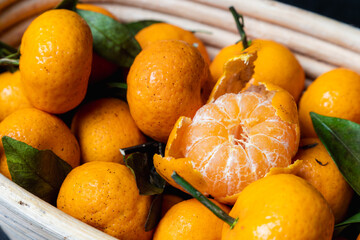 pile of mandarin orange on a wooden bucket, dark background