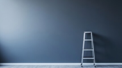 An empty room with an aluminum ladder leaning against the gray wall, emphasizing the readiness for work or creativity.