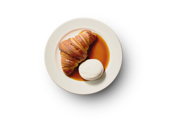 Golden-brown croissant served on a plate with a rich caramel sauce and a dollop of creamy mascarpone or whipped cream, offering a delightful balance of buttery pastry and sweet, creamy flavors.