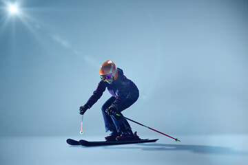 Young woman, sport lover, kier crouches in action pose, ready to glide, against gradient blue studio background. Concept of extreme sport, Christmas holidays. Ad