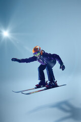 Skier leans into jump, her posture dynamic and expressive. Light blue backdrop enhances movement's fluidity. Concept of extreme sport, Christmas holidays, freestyle. Ad