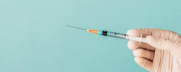 Syringe held by gloved hand against a teal background. Anti-aging and injection concept.