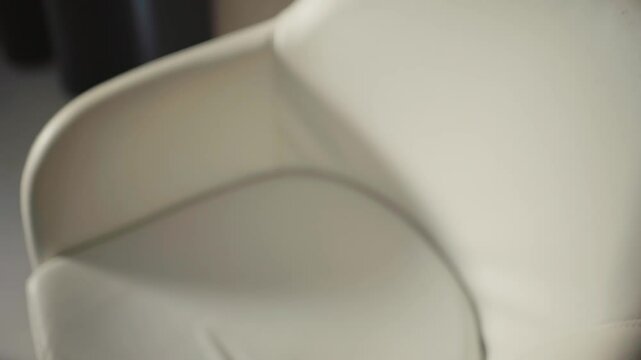A wooden acoustic guitar rests on a white chair in soft lighting creating a warm and inviting feel