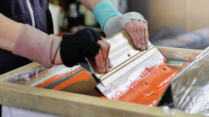 male hands with a squeegee. silk screen textile printery. manual screen printing. creating print on t-shirt