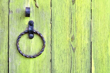 Old wooden door with aged metal door handle in the form of ring. Architectural background with old yellow wooden door