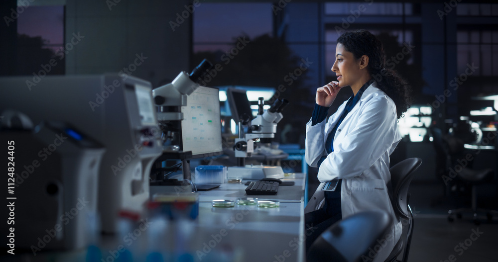 Poster Hispanic Female Scientist Working on a Computer in the Evening. Specialist Using a Gene Sequencing Online Software. Advanced Biotechnology Lab in a Medical Research and Development Center