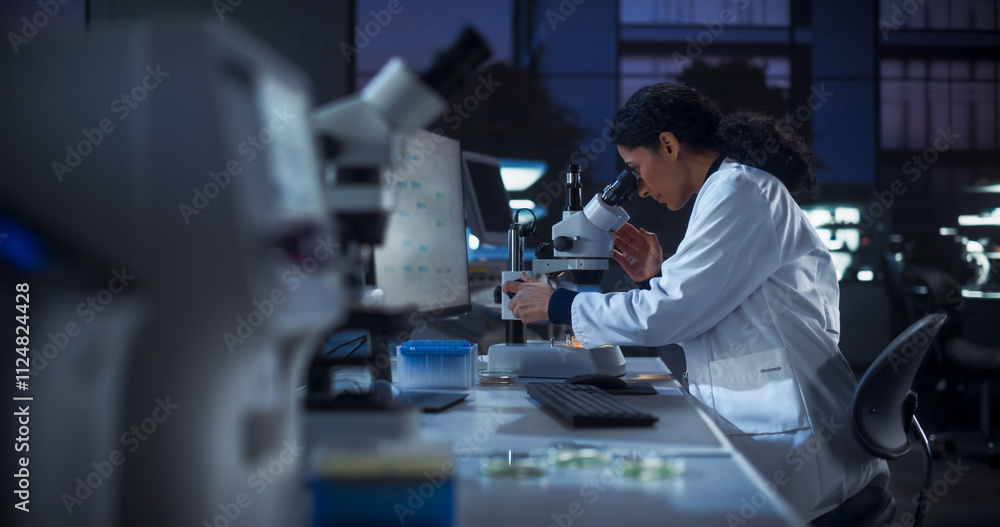 Aufkleber Medical Research and Development Laboratory: Multiethnic Female Scientist Using Computer and Looking at a Sample in a Petri Dish Under a Microscope. Advanced Genetic Engineering Lab at Night