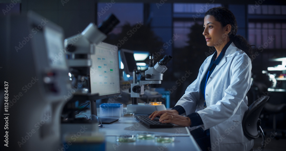 Poster hispanic female scientist working on a computer in the evening. specialist using a gene sequencing o