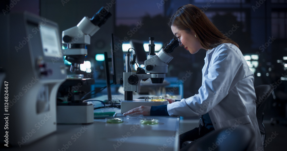 Poster Genetic Research Scientist Using Microscope in an Applied Science Laboratory in the Evening. Portrait of a Beautiful Asian Lab Engineer in White Coat Developing New Medical Products