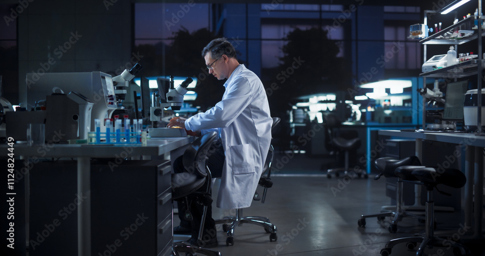 Poster portrait of a caucasian scientist working in a laboratory in the evening, using advanced microscope,