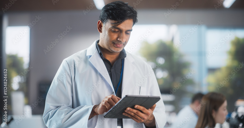 Poster portrait of an indian adult male scientist using tablet computer in a laboratory. professional resea