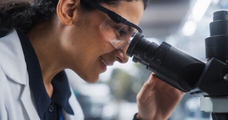 Portrait of a Beautiful Hispanic Student Working on a Research Project in University. Medical Research Scientist Looking at Biological Samples Under a Microscope in an Applied Science Laboratory