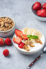 Healthy breakfast granola bowl with strawberries, banana and greek yogurt. Rich in protein and fiber. Top view, flat lay composition