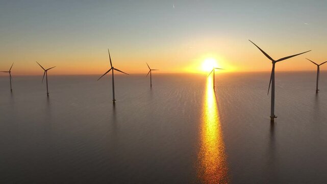 Offshore wind farm in the sea at sunrise or sunset. Aerial view of Windpark with wind turbines, windmills in Netherlands. Power plant, climate change, sustainable resources, green renewable energy. 4K