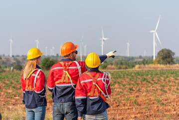 Three people are standing in front of a wind farm