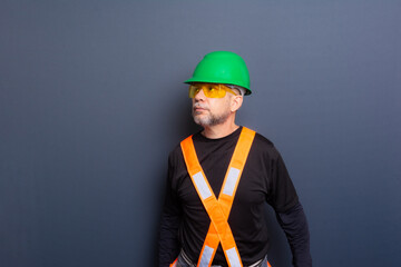 A civil worker wearing a green helmet, reflective vest and protective glasses. Posing for the...