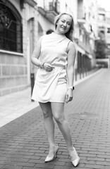 Happy woman in stylish dress walks along cobblestone street