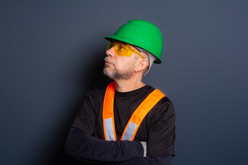 Photo of a civil worker wearing a green helmet, reflective vest and protective glasses. isolated on gray background.