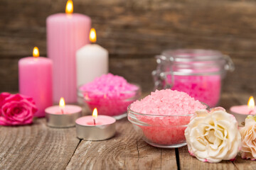 Sea salt for bath with aroma and rose flowers on textured wooden background. Pink sea salt. Spa treatments. Natural salt with herbs and essential oils. skincare concept. Meso for text. Copy space