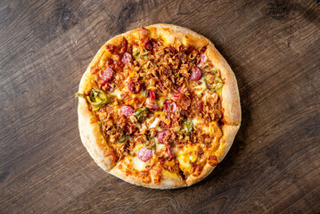 Delicious pizza topped with melted cheese, tender beef, mushrooms, pickles, and onions, sitting on a wooden surface. Ideal for food-related projects and culinary themes.