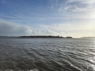 Spike Island in Ireland as it is seen from another island, with ocean waters and cloudy sky