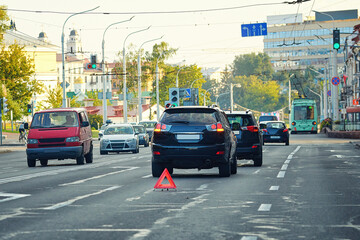 Rear-end collision scene in city with cars stopped and warning triangle placed on the road, road safety and accident response. Car accident showing rear-end collision with warning triangle on the road