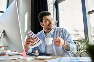 Handsomeness radiates as a man sips coffee and chooses color palettes in a stylish workspace.